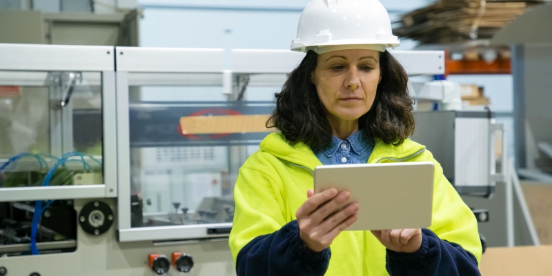 Focused female industrial worker using tablet computer onsite